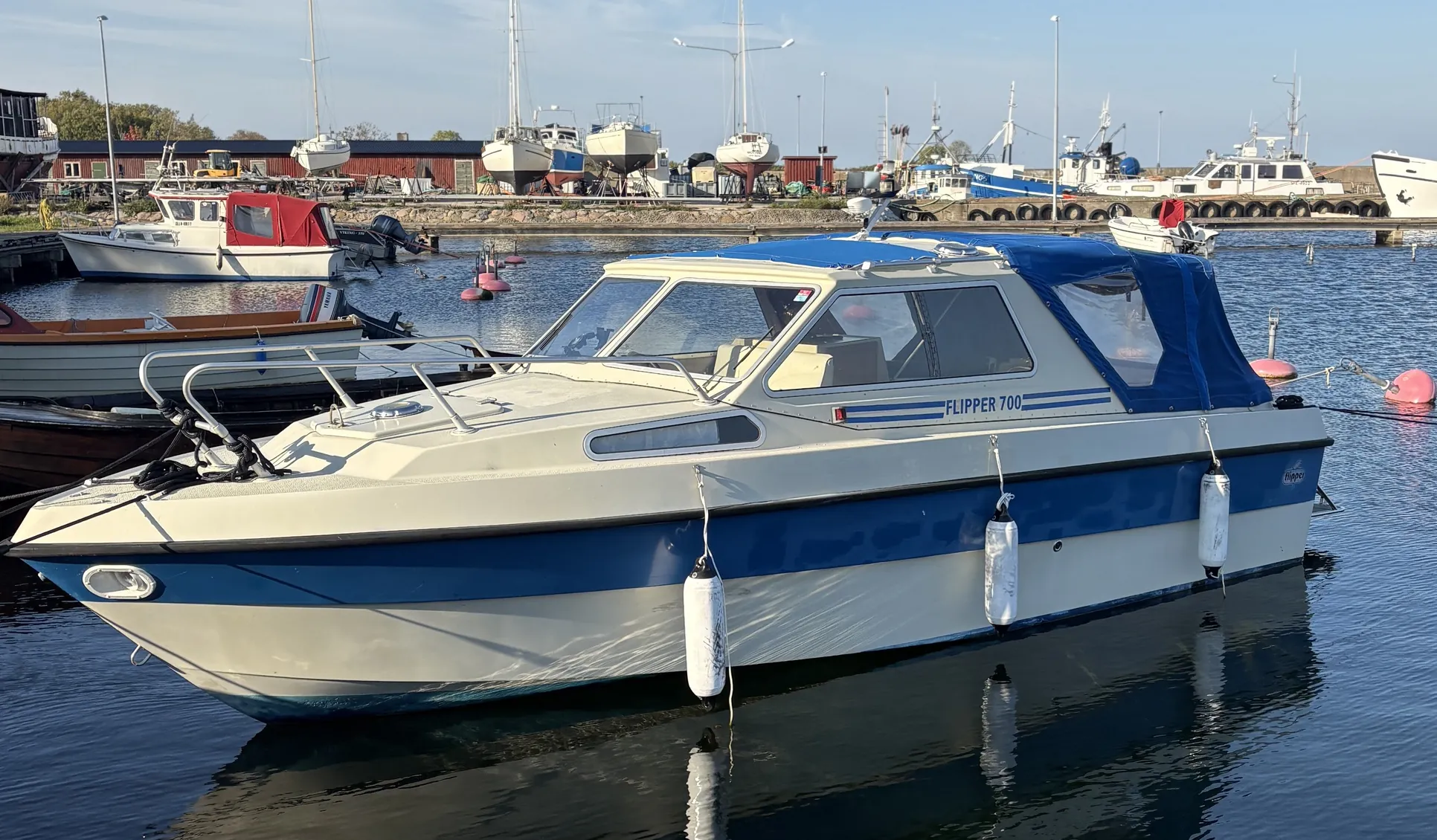 Flipper 700-båt med blå stripe i havn